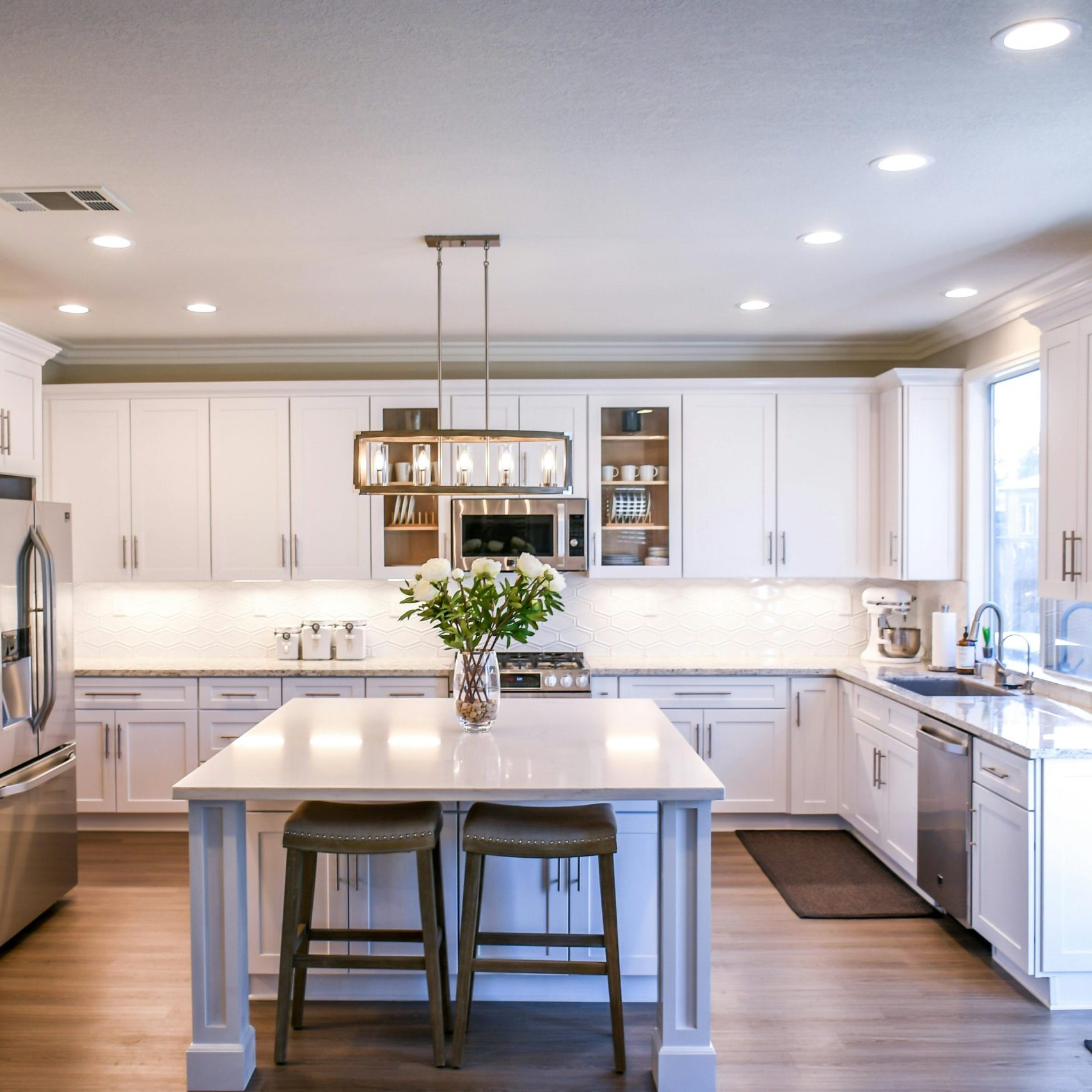 Spacious and elegant kitchen featuring white cabinetry, island, and stainless steel appliances.