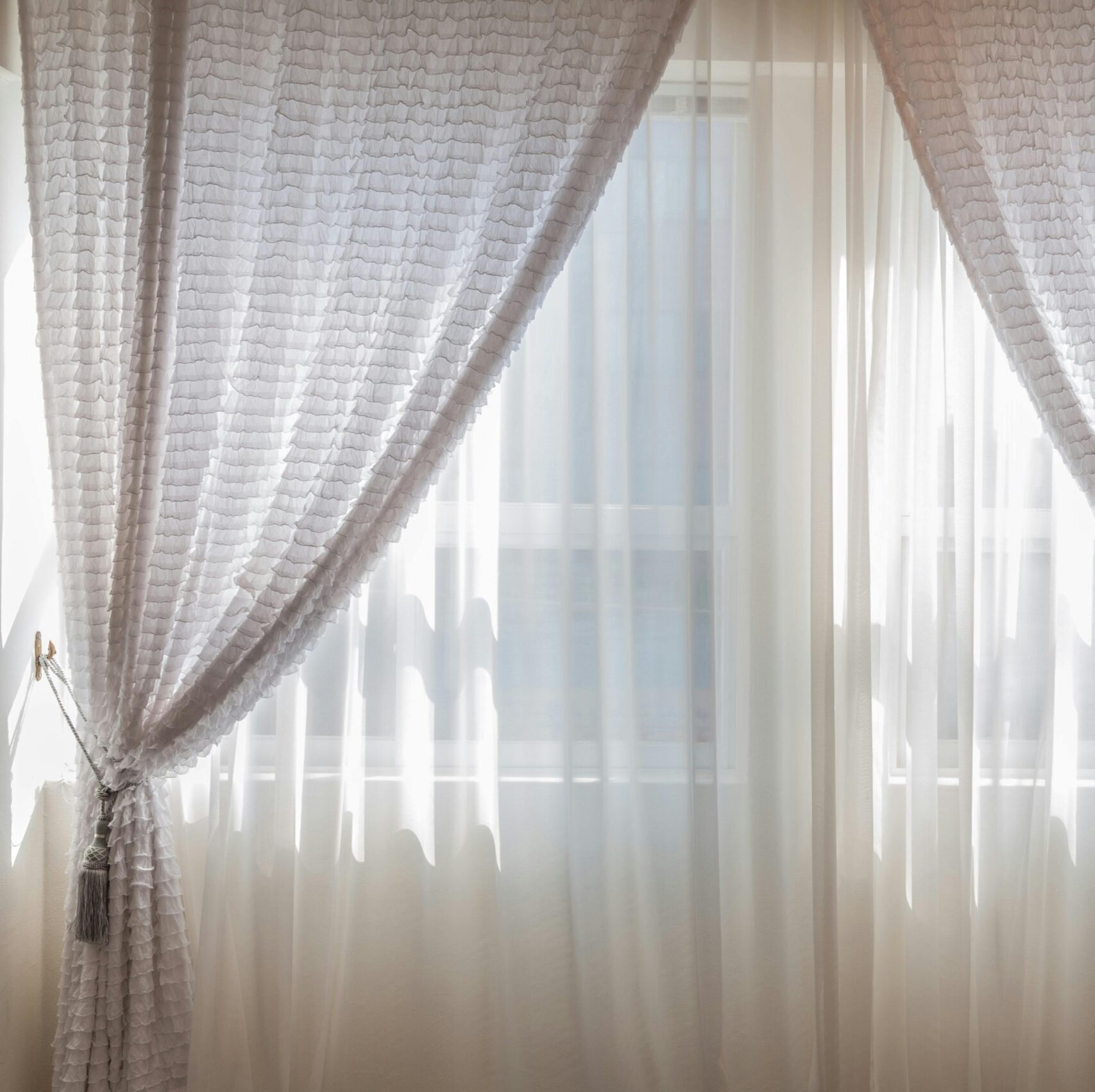 Sun shining through elegant white curtains in a cozy, modern interior setting.